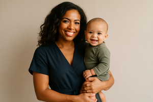 american mom wearing a jumpsuit carrying a super cute baby smiling towards the camera